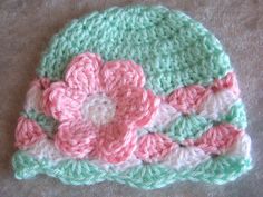 a crocheted hat with pink and green flowers