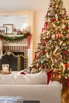 a living room with a christmas tree in the corner and a fire place on the other side