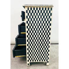 a black and white checkerboard cabinet with three drawers on each side, in front of a white wall