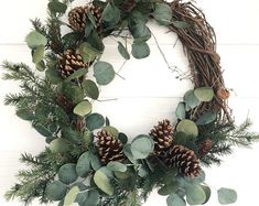 a wreath with pine cones and greenery on it