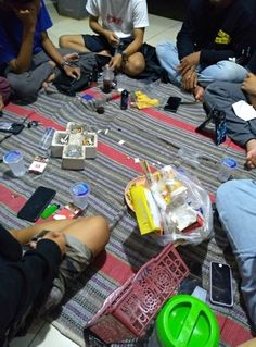 group of people sitting on the floor with cell phones and other items scattered around them