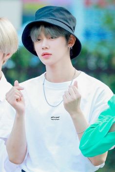 two young men wearing white shirts and black hats, one is pointing at the camera