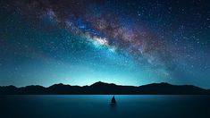 a boat floating on top of a lake under a night sky filled with lots of stars