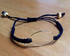 a bracelet with two circles on it sitting on a wooden table next to a pair of scissors