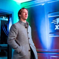 a man standing in front of an exit sign with his hands in his pockets and looking off to the side