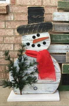 a snowman sitting on top of a wooden bench next to a small christmas tree