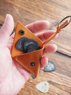 a hand holding a leather keychain with buttons in it