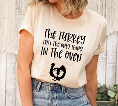 a woman wearing a t - shirt that says the turkey isn't the only thing in the oven