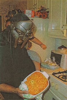 a person in a kitchen wearing a mask and holding a bowl of macaroni and cheese