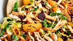 a salad with chicken, oranges and cranberries in it