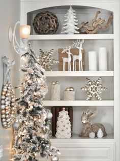 a decorated christmas tree in front of a white book shelf filled with ornaments and decorations