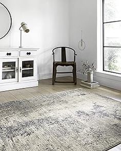 a living room with white furniture and a large rug on the floor in front of a window