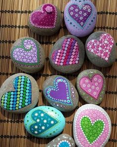 painted rocks with hearts on them sitting on a bamboo mat