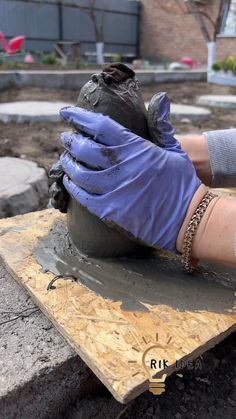 a person in blue gloves working on a clay pot