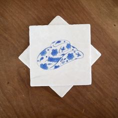 a blue and white coaster with a hat on it sitting on a wooden table top