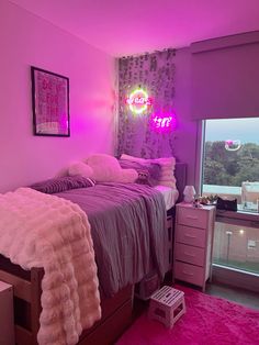 a bed room with a neatly made bed next to a large window and a pink rug