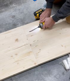 a man is using a drill to cut plywood planks with a power tool