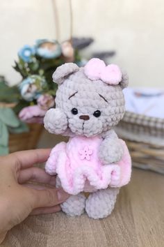 a hand holding a small crocheted teddy bear