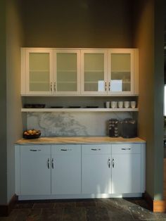 a kitchen with white cupboards and marble counter tops on the wall, along with an area rug