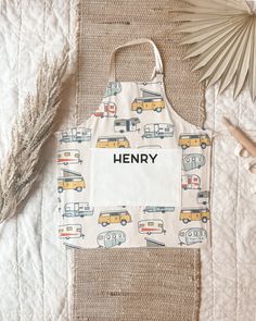 an apron with the word henry printed on it next to a palm leaf and other items