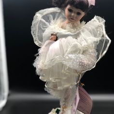 a doll is wearing a white dress and holding a pink tag