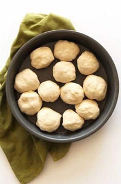 doughnuts are in a black bowl on a green cloth next to a napkin