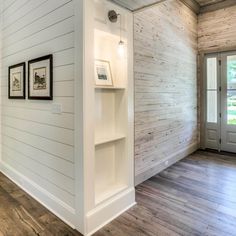 an empty room with wood floors and white walls, two framed pictures on the wall