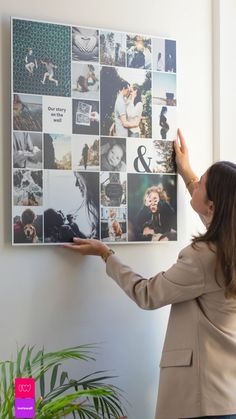 a woman placing pictures on the wall with her hands in front of her and touching it