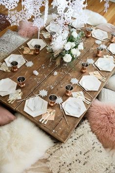 a wooden table topped with lots of white plates and silverware covered in snowflakes