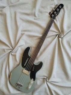 an electric guitar laying on top of a white sheet