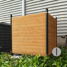 a large wooden box sitting in the grass next to a building with an air conditioner on it