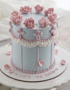 a blue and white cake with pink roses on it