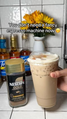 someone is holding up a drink in front of a counter with condiments on it