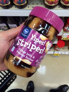 a hand holding a jar of peanut butter in front of shelves with shoes on the floor