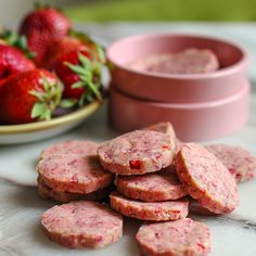 several sausage patties on a plate with strawberries in the back ground and two pink bowls