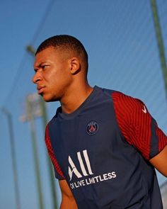 a young man holding a soccer ball in his hand and wearing a jersey with the word all on it