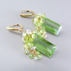 These green focal stones are absolutely stunning! They are celery green quartz in a baguette cut and the step cut faceteing is beautiful. The focals measure 21x10mm., with dozens of shaded green tourmaline and green amethystine Ethiopian opal rondelles draping down around the focals stones. The earrings measure 1 7/8 from the top of the gold filled lever back ear wires. I can easily switch out the lever backs for simple French style ear wires. Green Amethyst Gemstone Earrings, Simple French Style, Watermelon Tourmaline Necklace, Celery Green, Peacock Pearl, Step Cut, Tourmaline Necklace, Green Opal, Aquamarine Stone