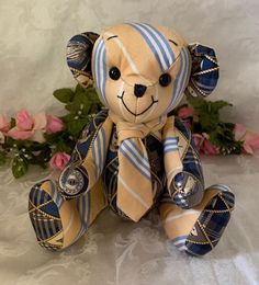 a teddy bear wearing a tie and sitting on a white surface with flowers in the background