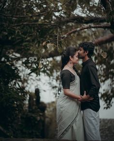 a man and woman standing next to each other under a tree