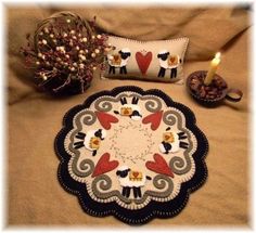 a table with a decorative plate, candle and some decorations on top of it next to a pillow