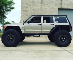 a jeep parked in front of a building with large tires on it's wheels