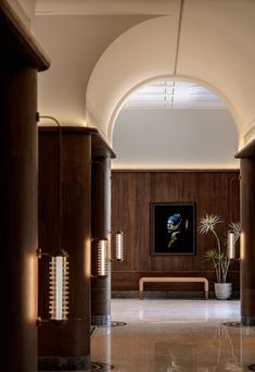 an arched hallway leading to a bench and potted plant