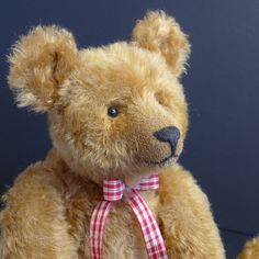 a brown teddy bear with a red and white checkered ribbon around it's neck