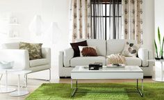 a living room filled with white furniture and green rugs