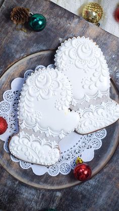 two heart shaped cookies sitting on top of a wooden plate next to christmas ornaments and decorations