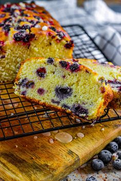 a loaf of lemon blueberry bread on a cooling rack next to some fresh blueberries