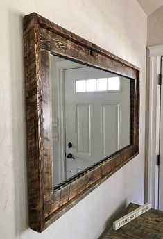 a mirror hanging on the side of a wall next to a wooden table and door