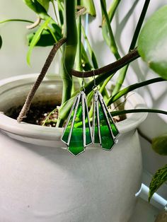 a potted plant with three green stained glass pieces hanging from it's stems