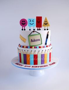 a multi - layered cake with colorful decorations and writing on the top is decorated in white frosting