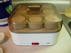 an electric waxing machine sitting on top of a counter next to some cups and saucers